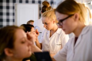 Słuchaczki ćwiczą makijaż na modelkach podczas zajęć