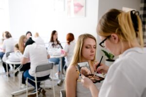 Słuchaczki ćwiczą makijaż na modelkach podczas zajęć