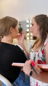 Uczennica wykonuje makijaż modelki podczas zajęć wizażu